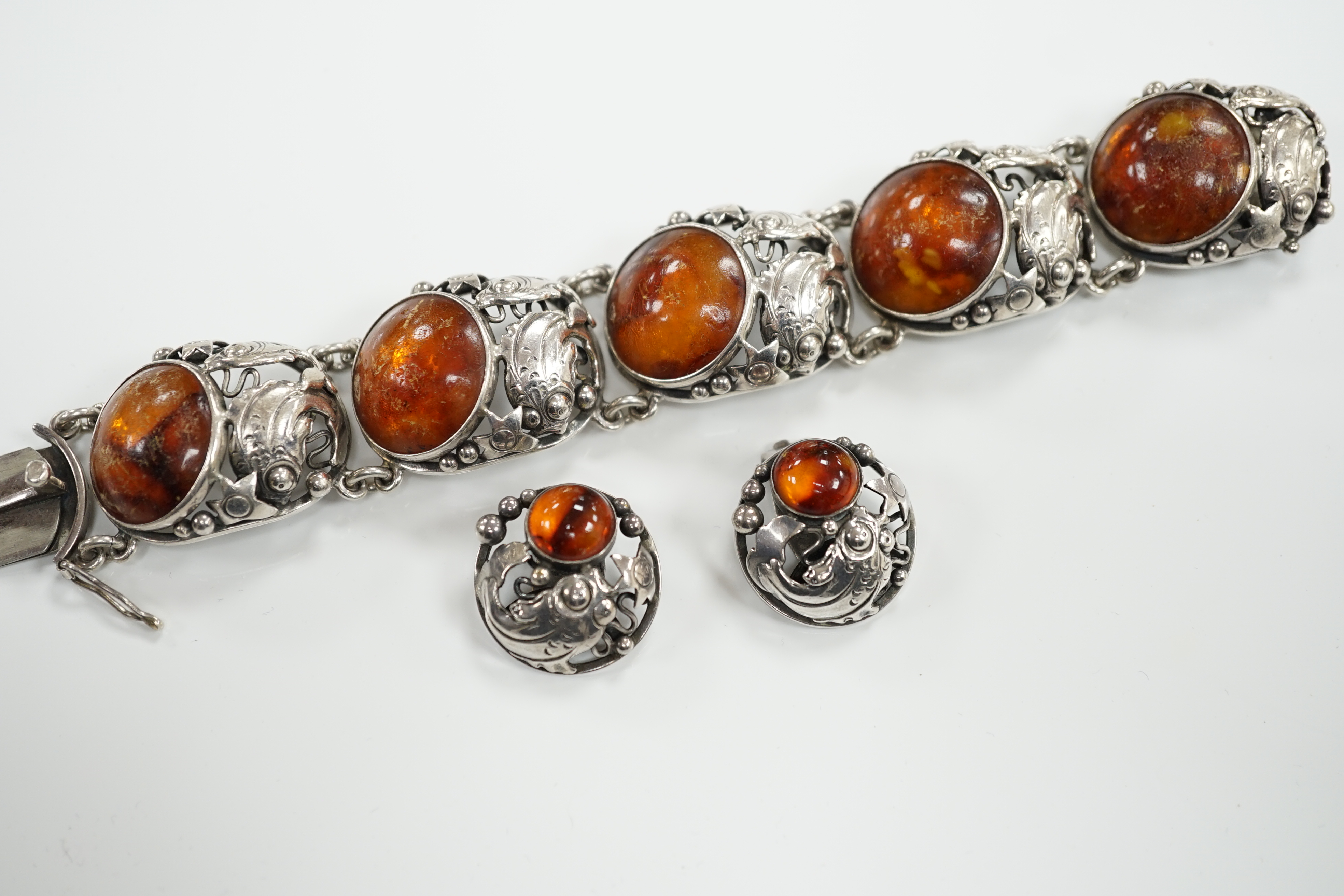 A Danish sterling 925 and amber set bracelet by Niels Erik From, comprising a bracelet 17.5cm and pair of matching circular ear clips, with fish, star and bead decoration.